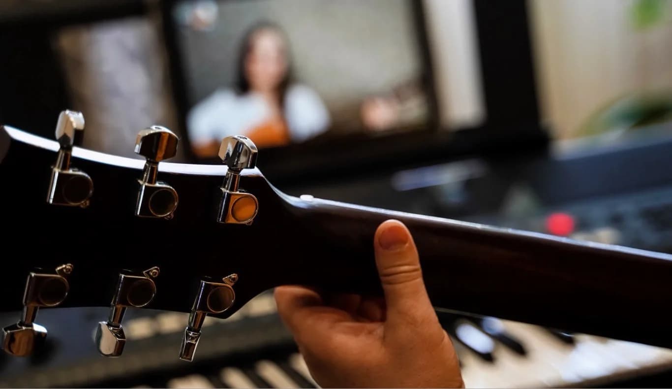 Student taking an online guitar lesson, zoomed in to the fret board